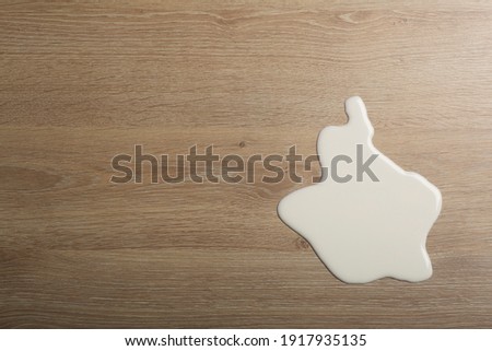 Wooden floor with overturned glass of white milk. Spilled  white milk on a wooden laminate (parquet) floor with moisture protection.	