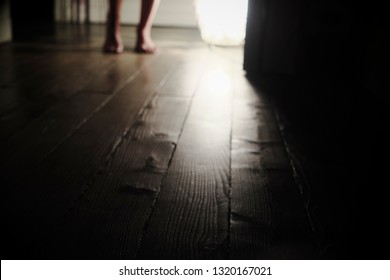 wooden floor with woman's feet in the background illuminated by a lamp - Powered by Shutterstock