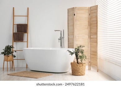 Wooden folding screen, bathtub and green houseplants in bathroom - Powered by Shutterstock