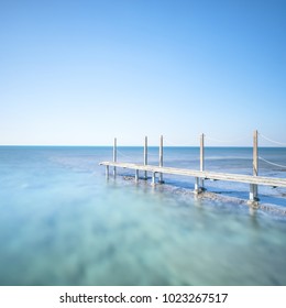 Wooden Footbridge Or Catwalk And Banister On Ocean Water. Long Exposure Photography.