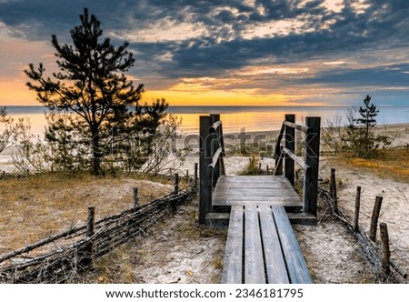 Wooden footpath leading to sandy beach of the Baltic Sea at dawn. Concept of happy, bliss, healthy vacation, sustainable lifestyle and carbon neutrality in nature of ecologically clean Baltic region