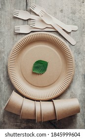 Wooden forks and paper cups with plates on wooden background. Eco friendly disposable tableware. Also used in fast food, restaurants, takeaways, picnics. Top view. Copy, empty space for text