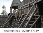 Wooden fortress wall against the sky. Medieval fortress with high walls. Wooden installation in the style of an ancient city. Stockade fence made of logs. Summer tourism and travel