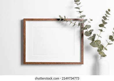 Wooden Frame Mockup On White Wall With Copy Space For Artwork, Photo Or Print Presentation In Minimalistic Interior With Eucalyptus Twig.