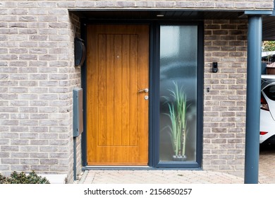 Wooden Front Door And Frosted Glass Window In A Porch In A Contemporary New Build With A Grey Pillar