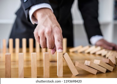 Wooden game strategy, Businessman hand stopping falling wooden dominoes effect from continuous toppled or risk, strategy and successful intervention concept for business. - Shutterstock ID 1193698420