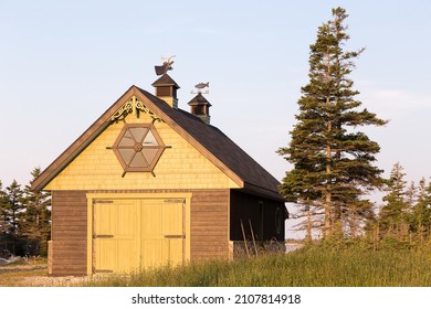 Wooden garage with dear and fish weathervanes seen during a late afternoon golden hour in summer, Port-Menier, Anticosti, Quebec, Canada