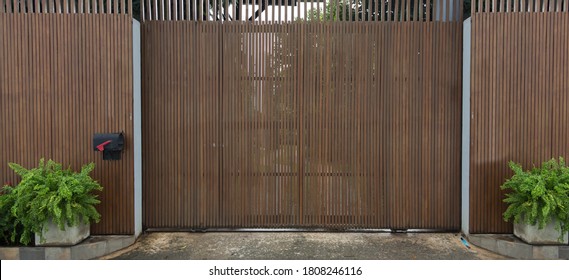 Wooden Garage Door Exterior Of Modern Home Background. Giant Gate Fencing With Wood And Iron Slice With Wheel