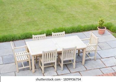 Wooden Garden Furniture On A Patio Terrace In A UK Back Garden With Lawn