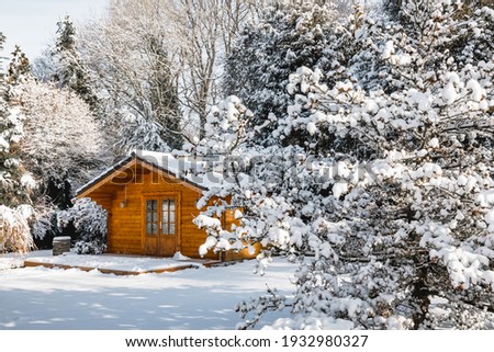 Wooden garden shed covered with snow. First snow. Winter in the garden	