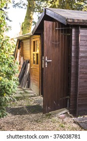 Wooden Garden Shed With The Door Open And A Neat Path Leading To The Entrance Under Shady Trees