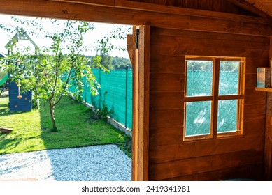 A wooden garden shed standing on a concrete foundation in a garden, view from inside the house.