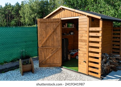 A wooden garden shed standing on a concrete foundation in a garden.