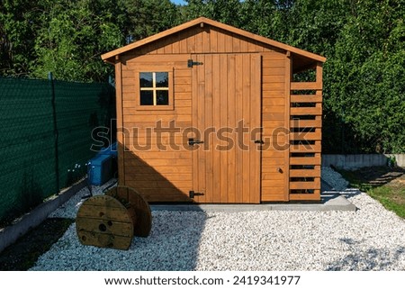 A wooden garden shed standing on a concrete foundation in a garden.