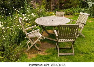 Wooden Garden Table And Chairs On A Lawn In A Pretty Traditional English Garden With No People And Surrounded By Flower Beds