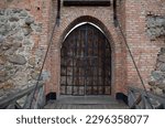 Wooden gate and bridge with ruined brick walls of an old stone castle close-up