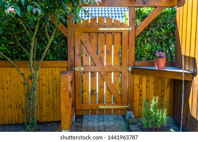 Wooden gate and fence on the back of the home garden. The gate is closed with a padlock.