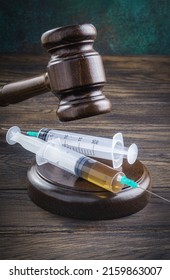 Wooden Gavel And Medical Syringes. Legal Cases Of Medical Negligence Or A Sentence For Drug Distribution Concept