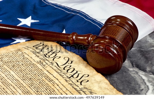 Wooden gavel on top of American flag and Bill of\
Rights document