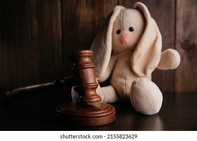 Wooden gavel and plush bunny in a dark court room. Law and children concept
