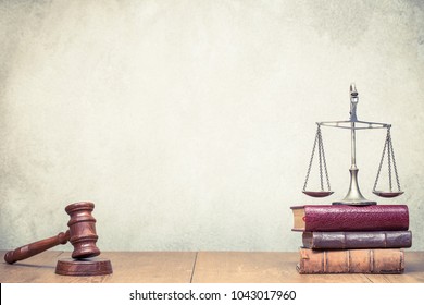 Wooden Gavel, Vintage Law Scales And Books On The Desk Front Concrete Wall Background. Symbols Of Justice. Retro Old Style Filtered Photo