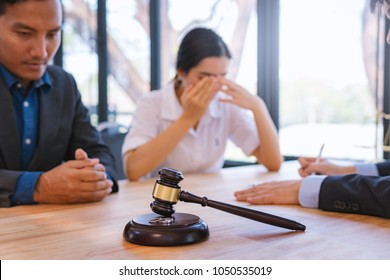 Wooden Gavel And Wedding Ring With Lawyer Working For Deciding On Marriage Divorce Clients In Background. Family Law Concept.