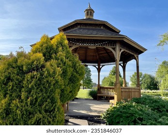 A wooden gazebo with a cement base and an ornate roof.