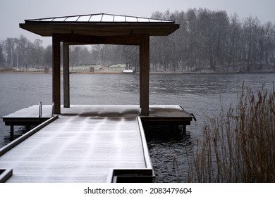 Wooden gazebo in the pier on the river with cape and iced fog over water in the background.