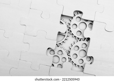 wooden gears under the puzzle, the concept of moving to the next level. Cog wheels coming out from underneath a jigsaw puzzle. solving the problem concept - puzzles and cogwheels.