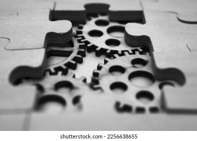 wooden gears under the puzzle, the concept of moving to the next level. Cog wheels coming out from underneath a jigsaw puzzle. solving the problem concept - puzzles and cogwheels - Shutterstock ID 2256638655