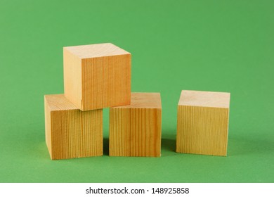 wooden geometric cube on a green background - Shutterstock ID 148925858