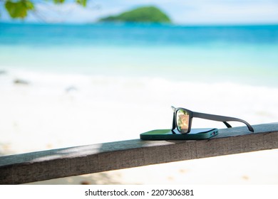 wooden glasses and mobile phone on the beach on holiday - Shutterstock ID 2207306381