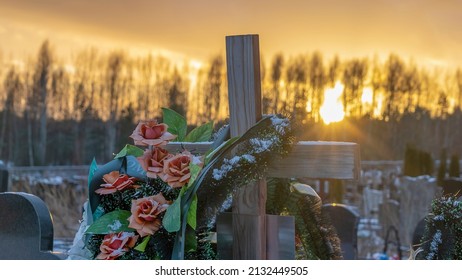 Wooden grave cross with artificial flowers at sunset. Orthodox traditional cemetery in snowy winter. Space for text. - Powered by Shutterstock