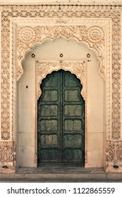 Wooden green door entrance in Mehrangarh (Meherangarh) Fort, Jodhpur, Rajasthan, India. Ornate brass door set in white marble frame.