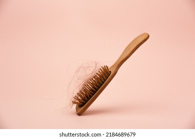 wooden hair brush with lost hair on the pink background - Shutterstock ID 2184689679