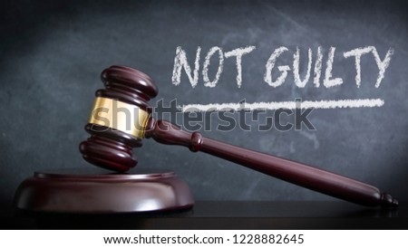 Wooden hammer in a courthouse at veredict of NOT GUILTY in a judgement. Hand written concept with chalk and empty copy space for Editor`s text.