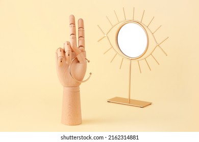 Wooden Hand With Bracelet And Mirror On Beige Background