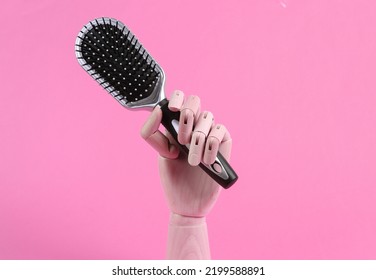 Wooden Hand Holding Hair Brush On Pink Background