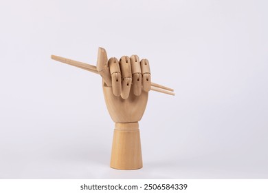 Wooden hand holding traditional chopsticks with closed hand Isolated on white background. Copy Space. Oriental food concept - Powered by Shutterstock