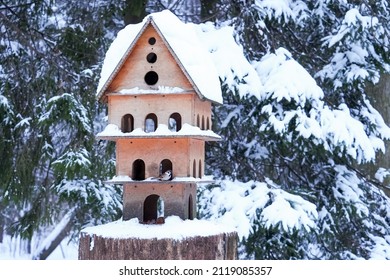 Wooden hand made big birdhouse in form of fairy house. Bird and small animal feeder in winter coniferous forest