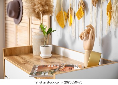 Wooden Hand With Magazine And Decor On Shelf Near Light Wall