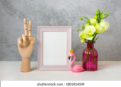 Wooden hand of manikin, figurine of pink flamingo, vase of flowers, photo frame on gray background and white wooden table Mock up Home decor, interior concept Scandinavian style Part of room design - Powered by Shutterstock