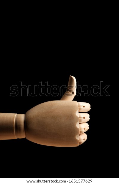 The wooden hand of a mannequin for\
drawing showssign to catch a car on a black background. Side view.\
Art model for drawing. Part of the body - hand,\
brush.
