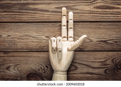 Wooden hand shows peace gesture on wooden background