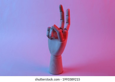 Wooden hand shows v gesture in pink blue gradient neon light