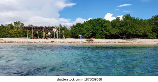 Wooden hand-built Jamaican shelter on a small luscious green island with white sand beach sitting in crystal-clear glistening blue Jamaican waters in the Port Royal Habour of Kingston Jamaica 
