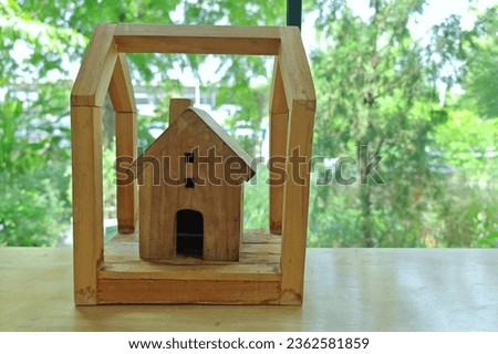 Wooden handcraft home toy on table by window with natural foliage green tree.