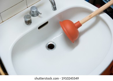 Wooden Handle Plunger With Suction Cup Next To Bathroom Sink Drain No People.