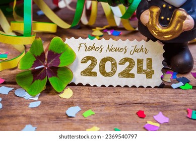 Wooden hang tag and slate with four leaf clover and sparklers with the german words for happy new year - frohes neues jahr 2024 on wooden weathered background - Shutterstock ID 2369540797