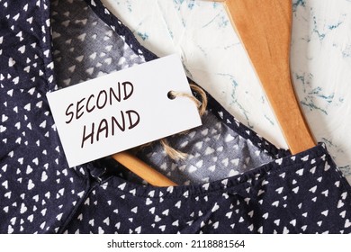 a wooden hanger for clothes, jacket and tag with inscription second hand on light background Slow fashion, circular economy, eco friendly sustainable shopping, thrifting second hand shop concept.